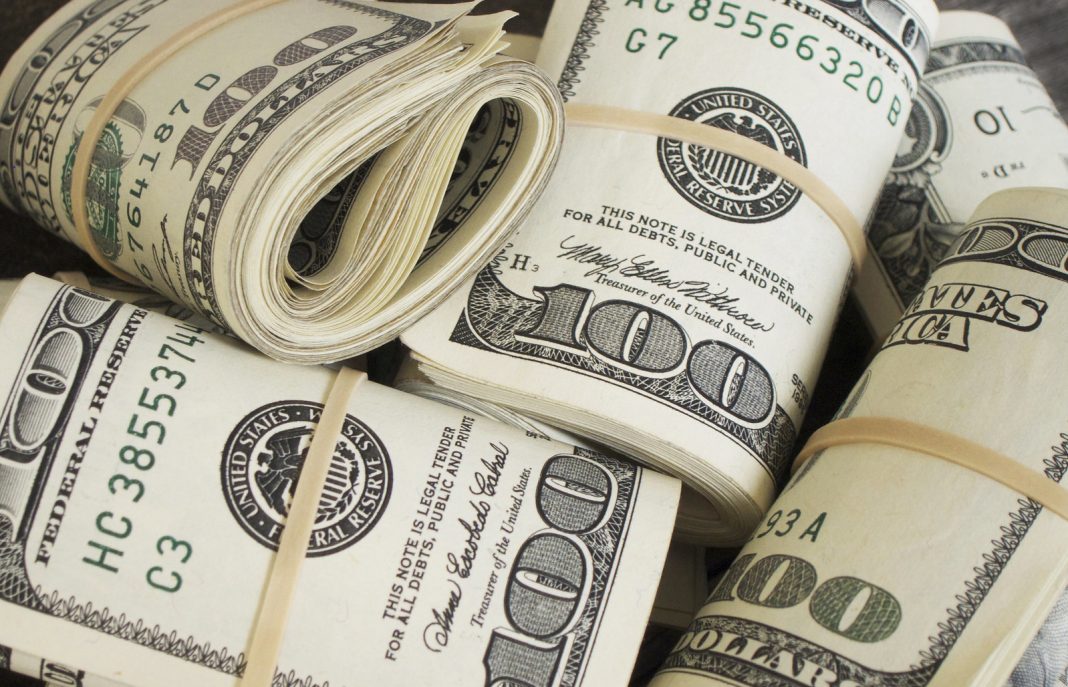 Several bundles of U.S. $100 bills wrapped with rubber bands, stacked closely together. The image emphasizes cash, wealth, and large amounts of money.