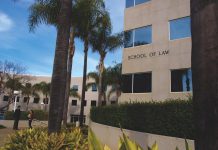 UC Irvine School of Law building surrounded by palm trees and landscaping with “SCHOOL OF LAW” displayed on the exterior wall.